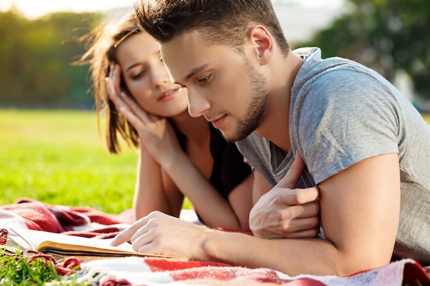Jeune beau couple souriant, lecture, repos au parc