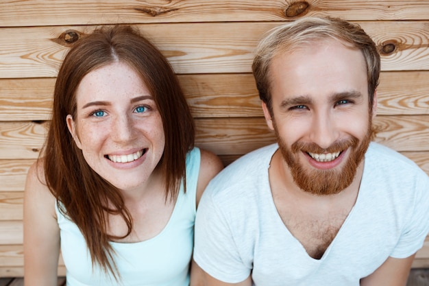 Jeune beau couple souriant, posant sur fond de planches en bois