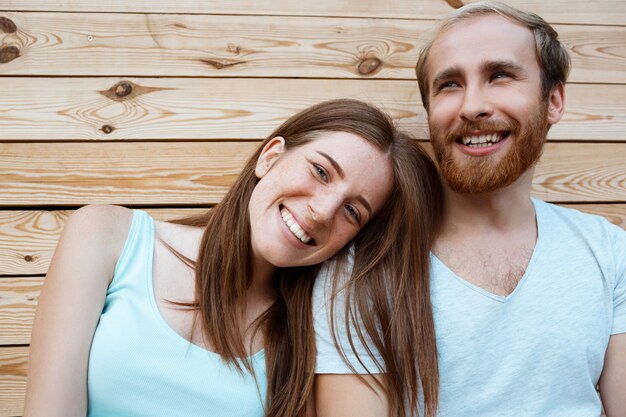 Jeune beau couple souriant, posant sur fond de planches en bois