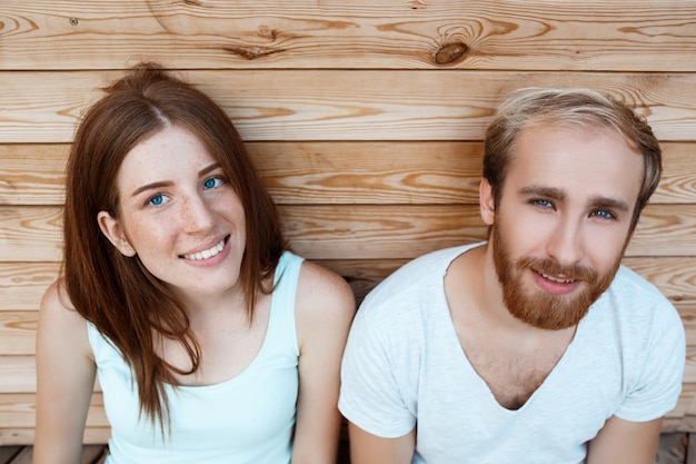 Jeune beau couple souriant, posant sur fond de planches en bois
