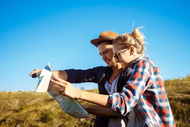 Photo gratuite jeune beau couple souriant, à la recherche d'un itinéraire sur la carte