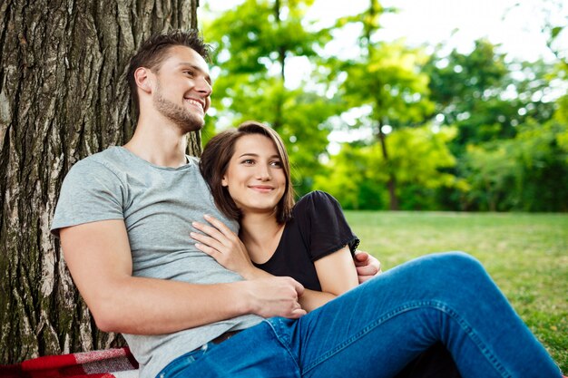 Jeune beau couple souriant, reposant sur un pique-nique dans le parc.