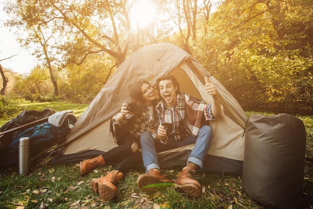 Jeune beau couple en tenue décontractée assis dans la tente dans la forêt