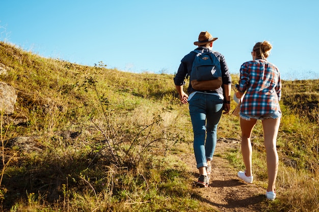 Jeune beau couple de voyageurs en remontant la colline