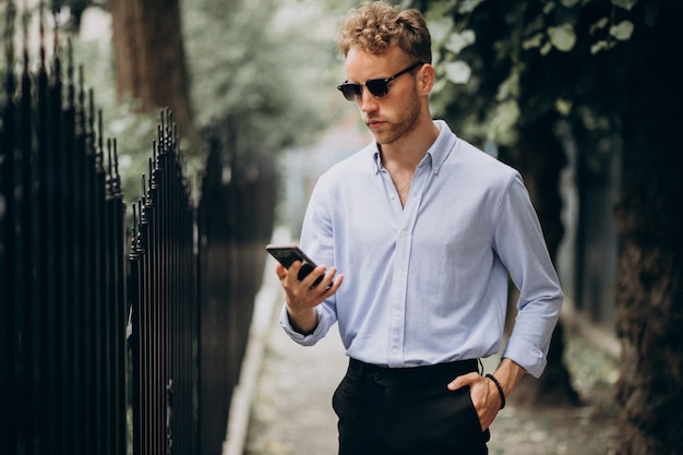 Jeune, beau, homme, utilisation, téléphone, dehors, rue