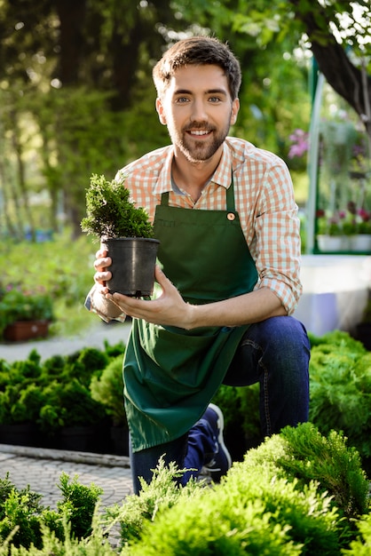 Jeune beau jardinier joyeux souriant, en prenant soin des fleurs