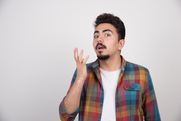 Jeune beau mec confus expression avec les bras et les mains levées.