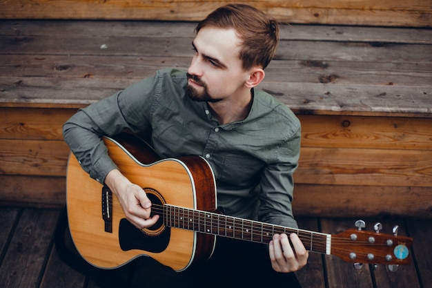 Photo gratuite jeune beau mec joue de la guitare, ramasse un accord, musicien de rue