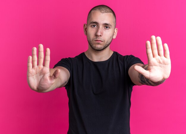 Jeune beau mec portant un t-shirt noir - isolé sur fond rose