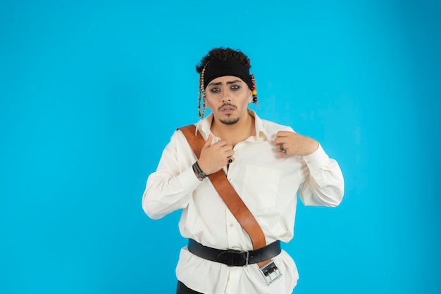 Jeune beau pirate debout sur fond bleu et regardant la caméra. Photo de haute qualité