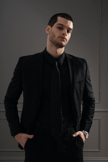 Jeune bel homme d'affaires en chemise noire et costume noir