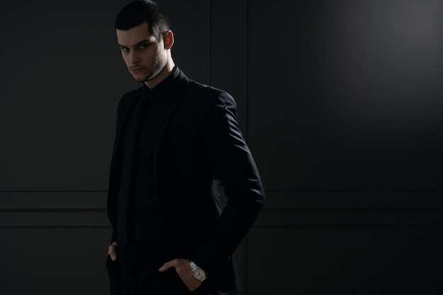 Jeune bel homme d'affaires en chemise noire et costume noir