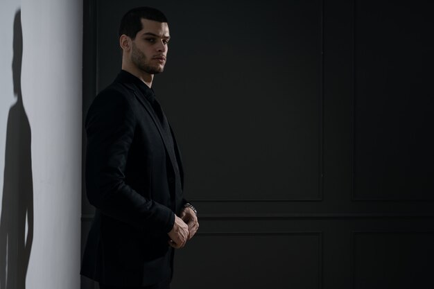 Jeune bel homme d'affaires en chemise noire et costume noir