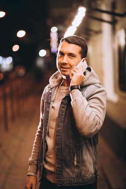 Jeune bel homme à l'aide de téléphone la nuit dans la rue