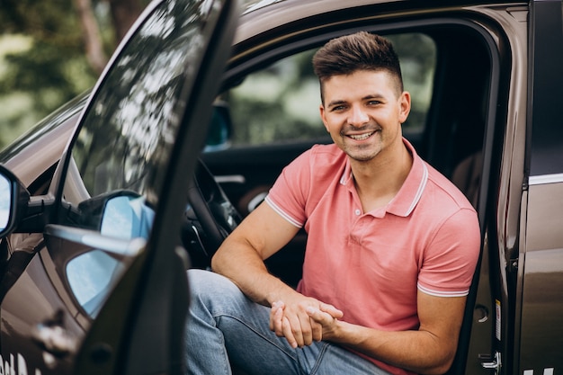 Jeune bel homme assis dans la voiture