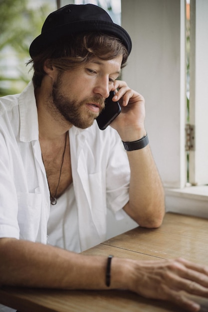 Un jeune bel homme au look décontracté appelle au téléphone, parle au téléphone.