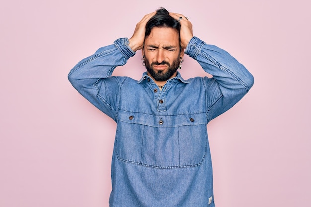 Photo gratuite jeune bel homme bohème hispanique portant un style hippie sur fond rose souffrant de maux de tête désespérés et stressés parce que la douleur et la migraine mains sur la tête