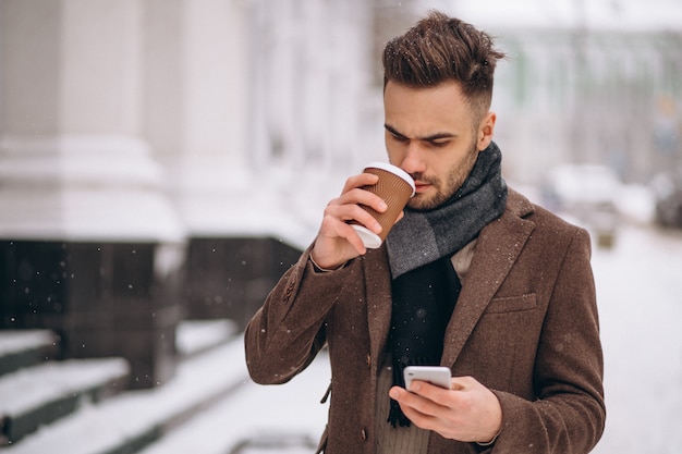 Jeune bel homme buvant du café et parler au téléphone