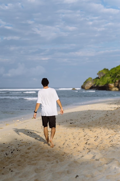 Jeune bel homme avec un charmant sourire en lunettes de soleil sur la plage.