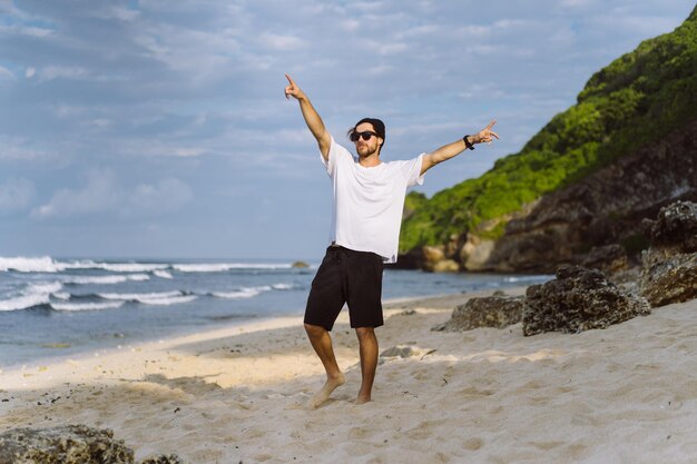 Jeune bel homme avec un charmant sourire en lunettes de soleil sur la plage.