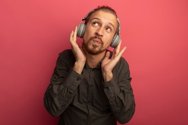 Jeune bel homme en chemise grise avec un casque sur la tête à la perplexité