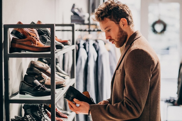 Jeune bel homme, choisir des chaussures dans un magasin