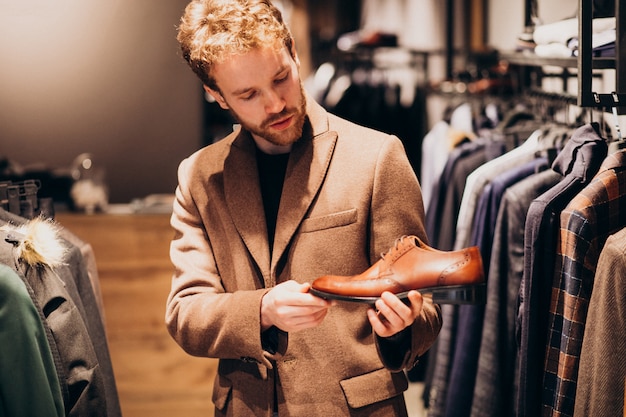 Jeune bel homme, choisir des chaussures dans un magasin