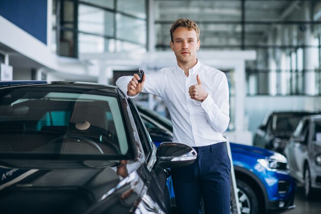 Jeune bel homme choisissant une voiture dans une salle d'exposition