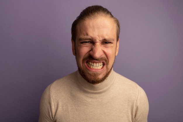 Jeune bel homme en col roulé beige avec visage en colère irrité