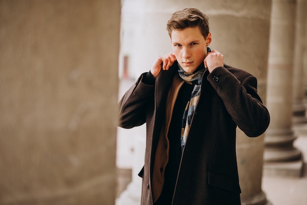 Jeune bel homme dans un manteau à l'extérieur de la rue