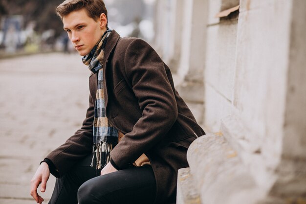 Jeune bel homme dans un manteau à l'extérieur de la rue