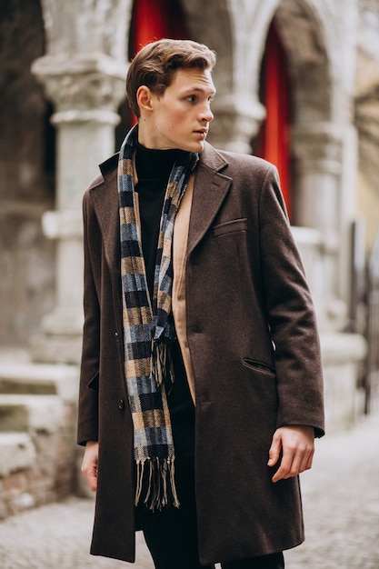 Jeune bel homme dans un manteau à l'extérieur de la rue