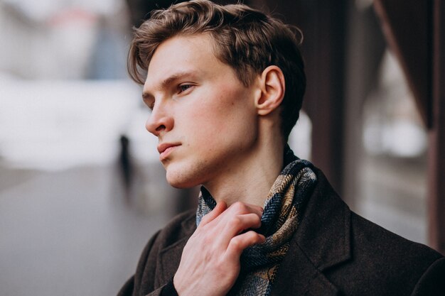 Jeune bel homme dans un manteau à l'extérieur de la rue