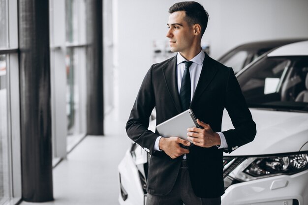 Jeune bel homme dans la salle d'exposition de voiture