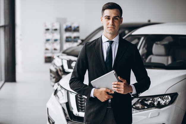 Jeune bel homme dans la salle d'exposition de voiture