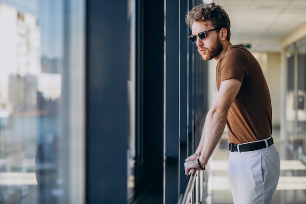 Jeune bel homme debout près de la fenêtre à l'aéroport