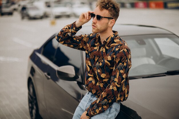 Jeune bel homme debout en voiture