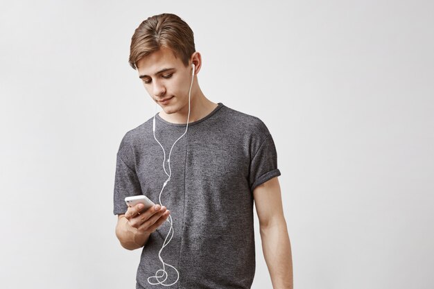 Jeune bel homme écoute de la musique dans le smartphone.