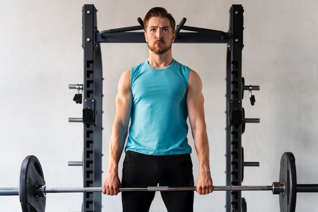 Photo gratuite jeune bel homme exerçant au gymnase pour la musculation