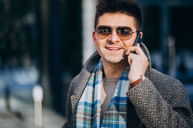 Jeune bel homme à l'extérieur à l'aide de téléphone