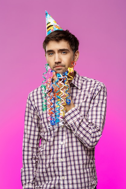 Jeune bel homme avec une fausse barbe pensant à la fête d'anniversaire.