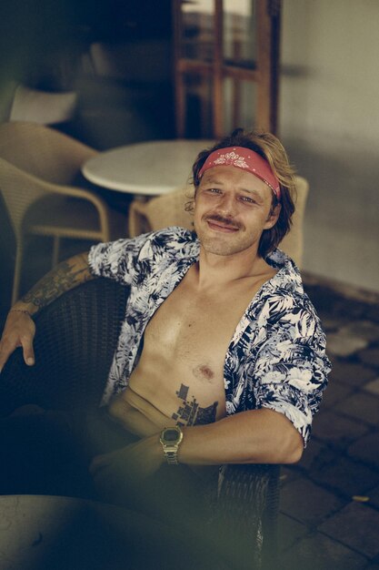 Jeune bel homme hippie dans un bandana rouge, avec un torse nu dans un café à Bali. Heureux homme souriant