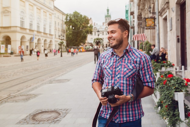 Jeune bel homme hipster marchant avec appareil photo sur la rue de la vieille ville