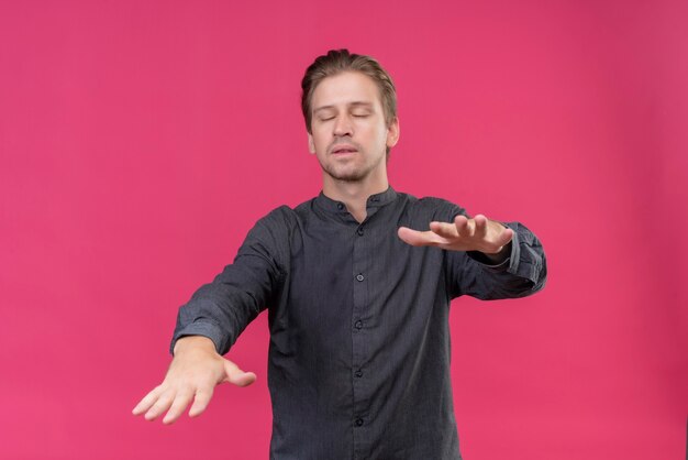 Jeune bel homme marchant avec les yeux fermés tendant ses mains