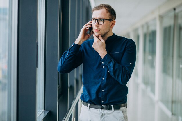 Jeune bel homme parlant au téléphone au bureau