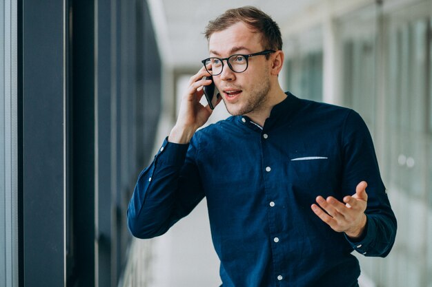 Jeune bel homme parlant au téléphone au bureau