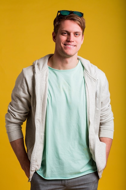 Photo gratuite jeune bel homme portant un t-shirt décontracté debout sur un mur jaune à la recherche d'un sourire sur le visage, expression naturelle. rire confiant.