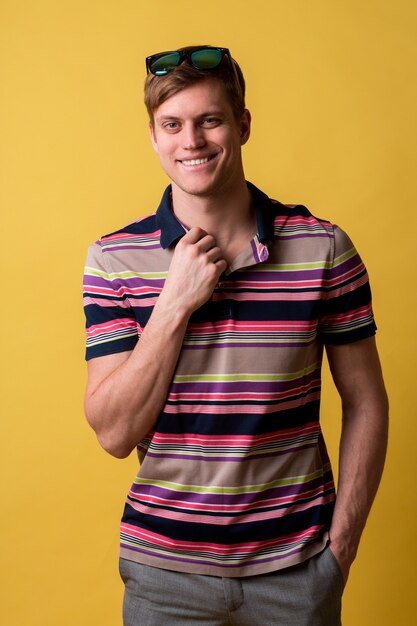 Jeune bel homme portant un t-shirt décontracté debout sur un mur jaune à la recherche avec le sourire sur le visage, expression naturelle. Rire confiant.