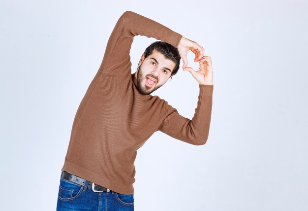 Jeune bel homme portant des vêtements décontractés souriant et faisant la forme du symbole du coeur avec les mains. photo de haute qualité