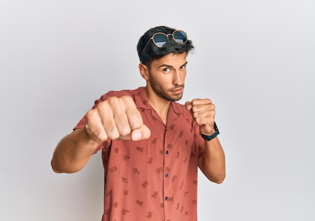 Jeune bel homme portant des vêtements d'été décontractés frappant le poing pour lutter contre la menace d'attaque agressive et en colère et la violence